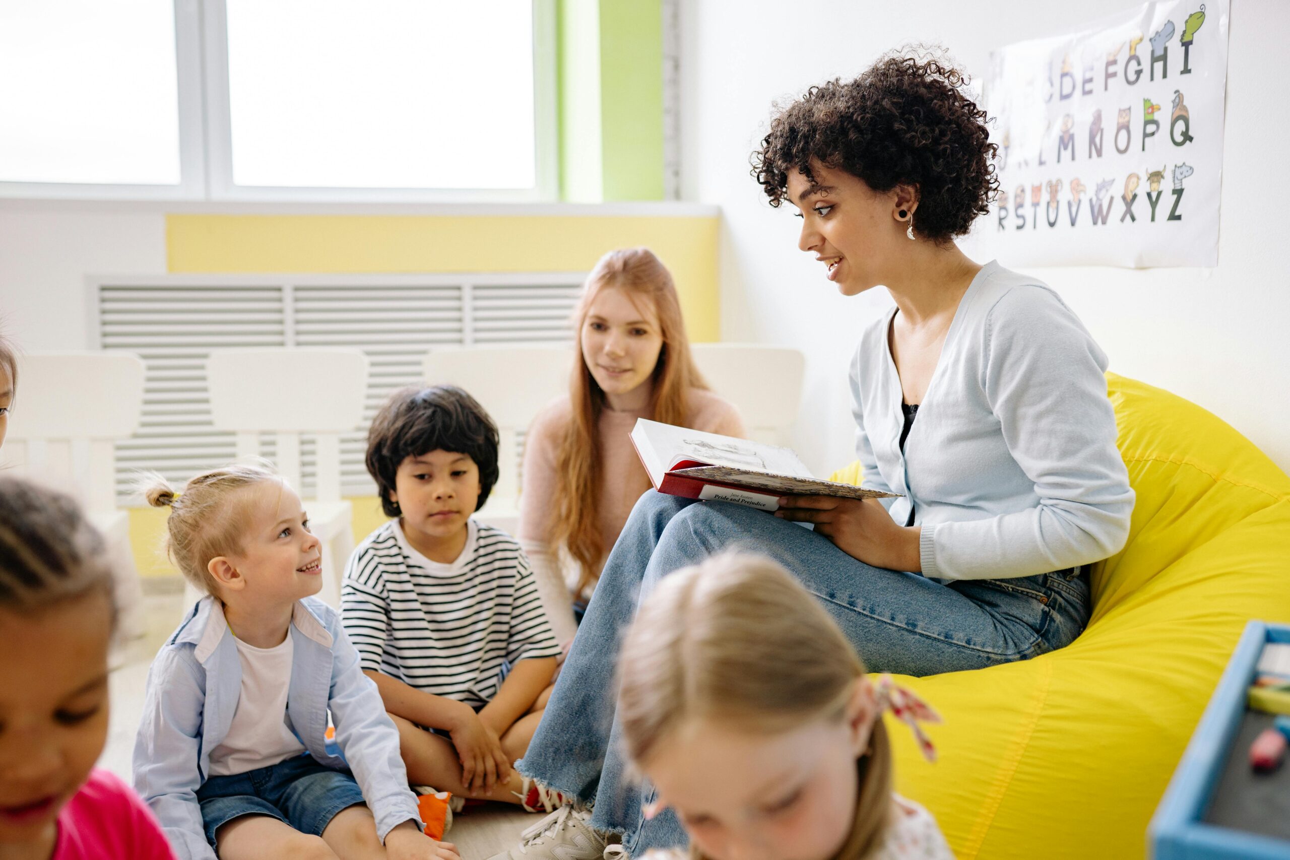 Teacher reading to preschool kids in a colorful classroom setting.